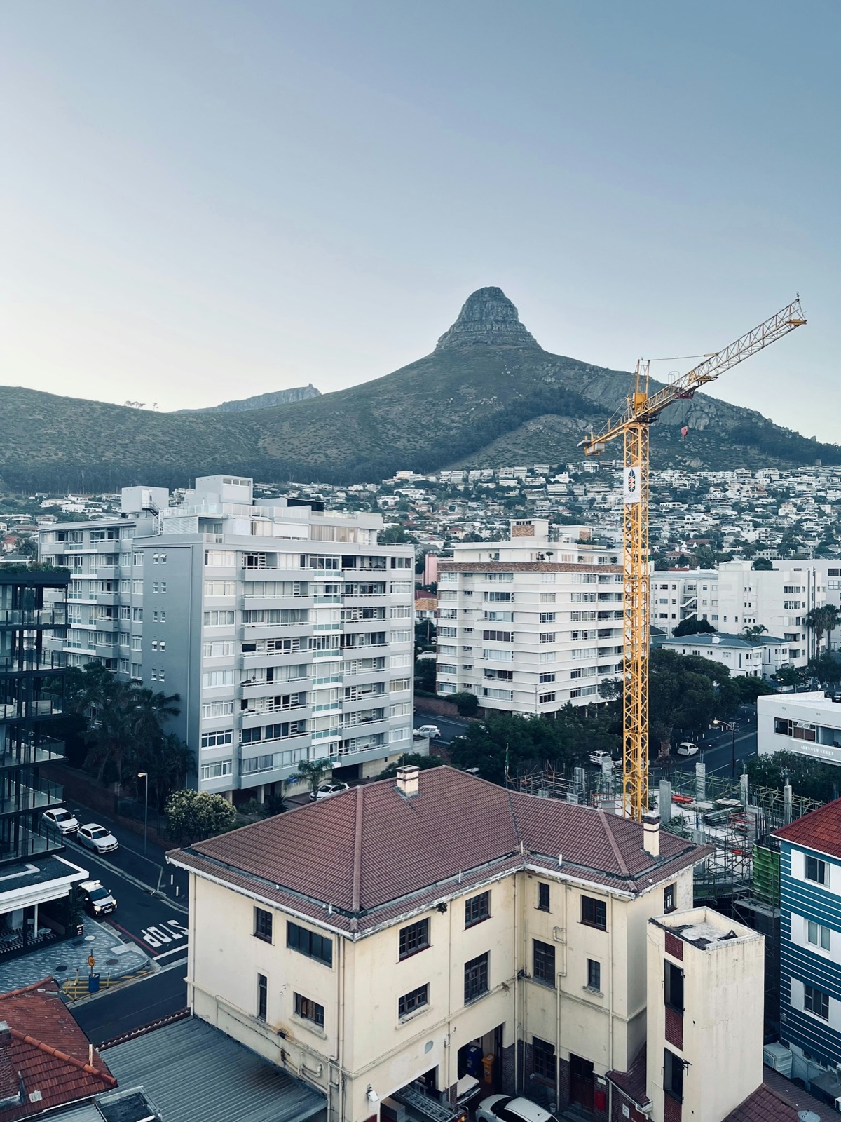 A residential building under construction at golden hour, tower crane on the rooftop.