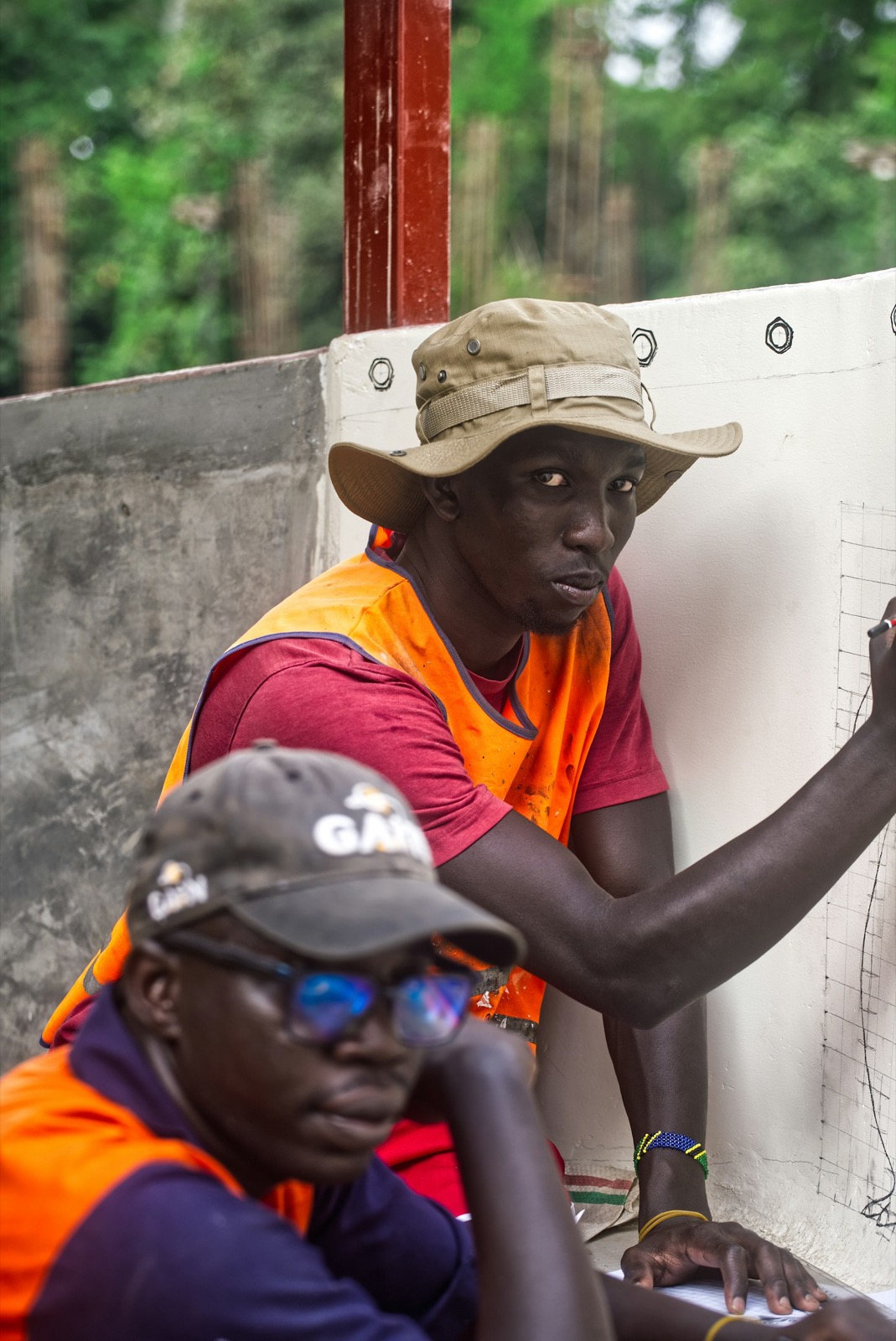 A BANEC engineer at a construction site, reviewing a drawing on a site wall.