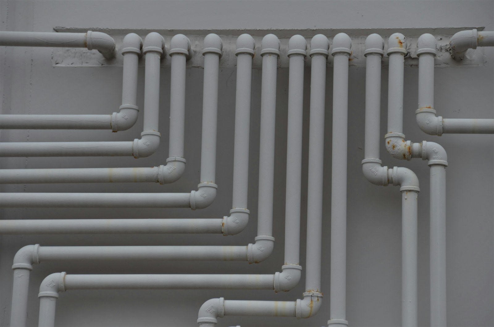 Plumbing pipework running along a wall.