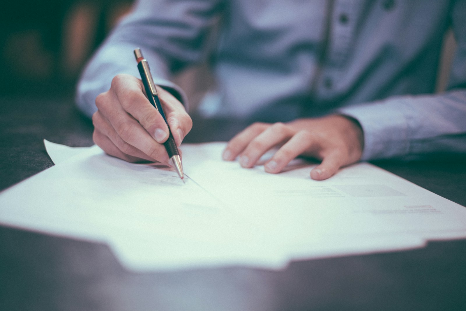 A contract being signed with a pen.