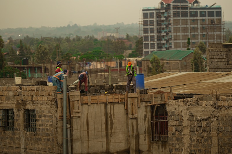 A crew building a blockwork wall on an active site above the city.