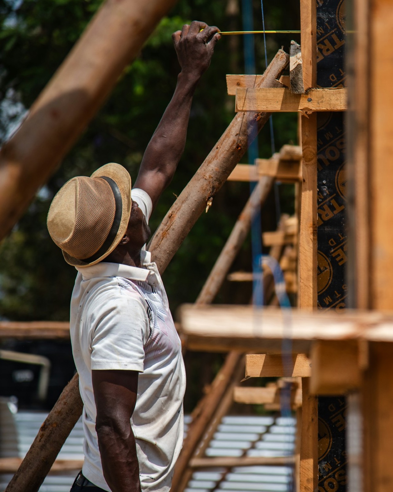 A Ugandan carpenter measuring a hardwood frame for a roof truss.