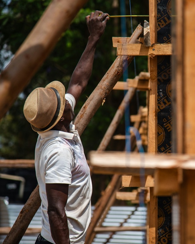 A Ugandan carpenter measuring a hardwood frame for a roof truss.