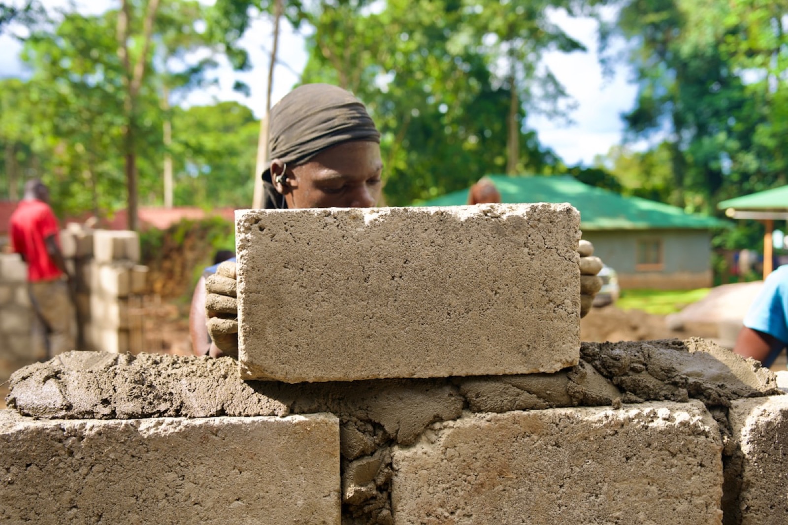 A Ugandan mason laying a course of concrete blocks.